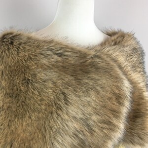 May include: A brown faux fur shawl with a soft, fluffy texture. The shawl is draped over a white mannequin.