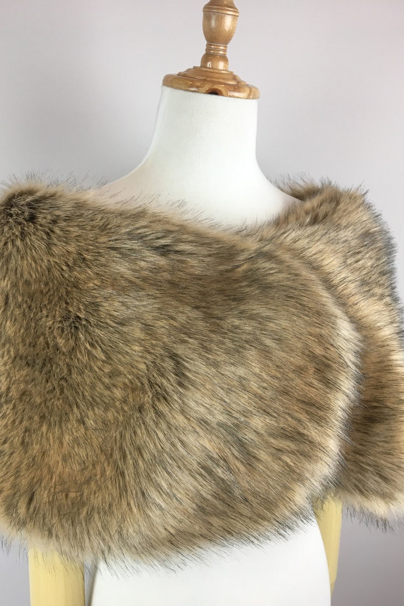 May include: A brown faux fur shawl with a soft, fluffy texture. The shawl is draped over a white mannequin.
