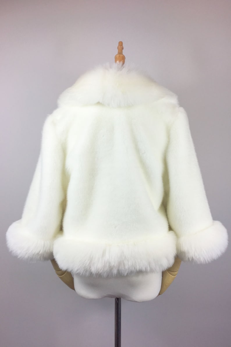 May include: White faux fur jacket with a large collar and cuffs. The jacket is on a white mannequin.