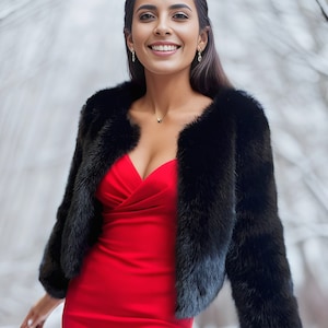 May include: A woman wearing a red dress and a black fur jacket. She is smiling and looking at the camera.