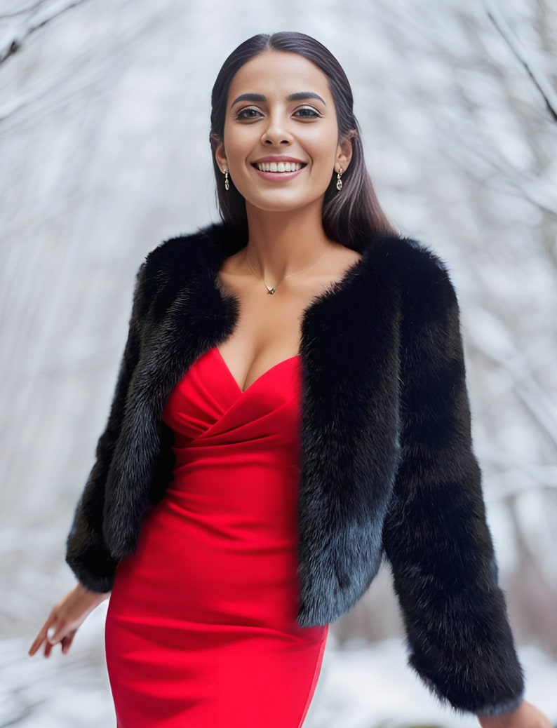 May include: A woman wearing a red dress and a black fur jacket. She is smiling and looking at the camera.