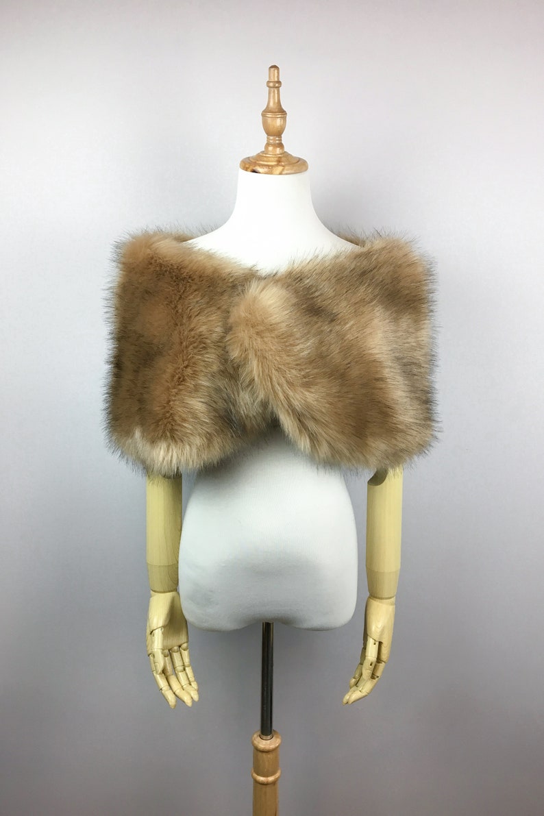 May include: A brown faux fur shawl on a white mannequin. The shawl is soft and fluffy, and it would be perfect for a winter wedding or a special occasion.