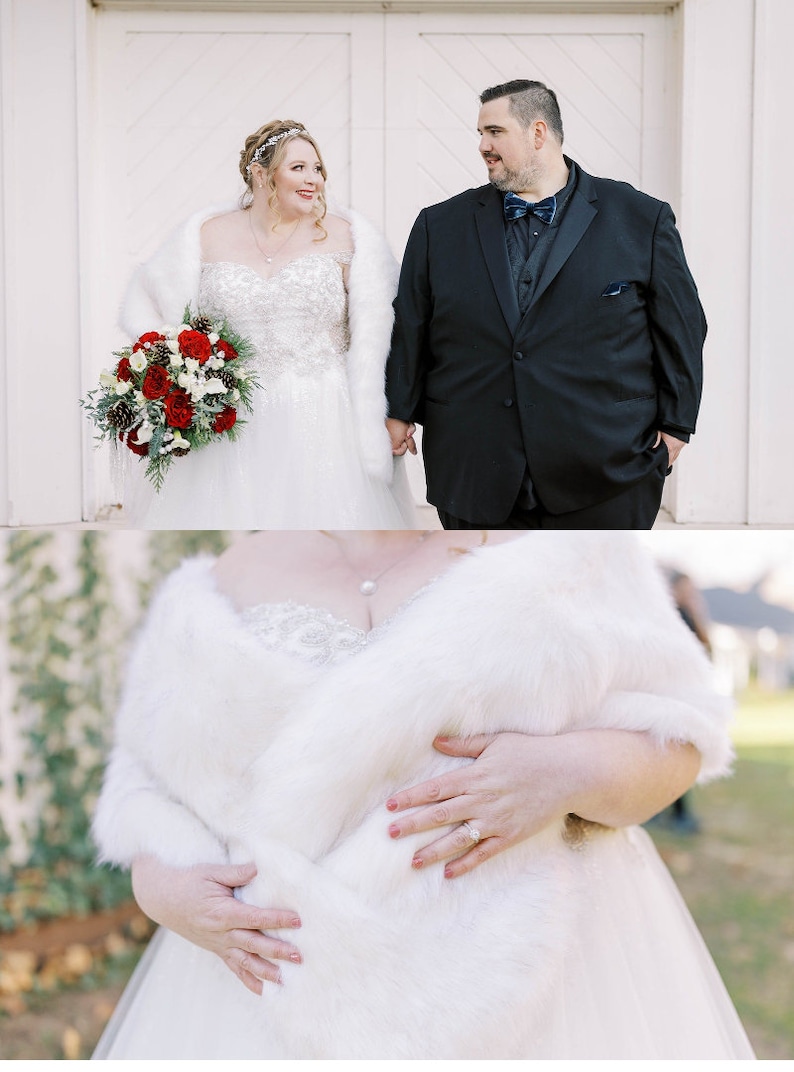 May include: A bride and groom are standing outside on their wedding day. The bride is wearing a white wedding dress with a white fur shawl and a bouquet of red roses. The groom is wearing a black suit with a black bow tie.