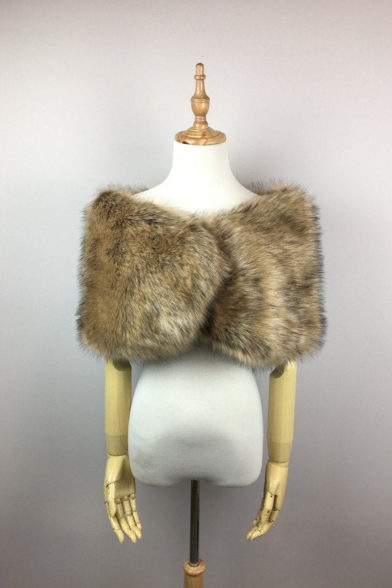 May include: A brown faux fur shawl with a soft, fluffy texture. The shawl is draped over a white mannequin.