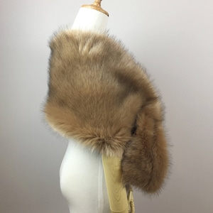 May include: A brown faux fur shawl draped over a white mannequin. The shawl is soft and fluffy, and it would be perfect for adding a touch of warmth and elegance to any outfit.