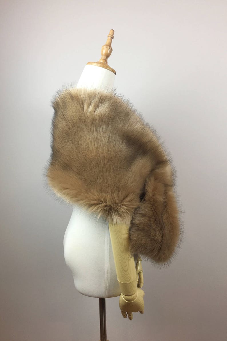 May include: A brown faux fur shawl draped over a white mannequin. The shawl is soft and fluffy, and it would be perfect for adding a touch of warmth and elegance to any outfit.