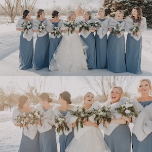 May include: A group of bridesmaids in dusty blue dresses with white faux fur wraps stand in a snowy outdoor setting. They are holding bouquets of white flowers and smiling. The bride is in the center wearing a white wedding dress.
