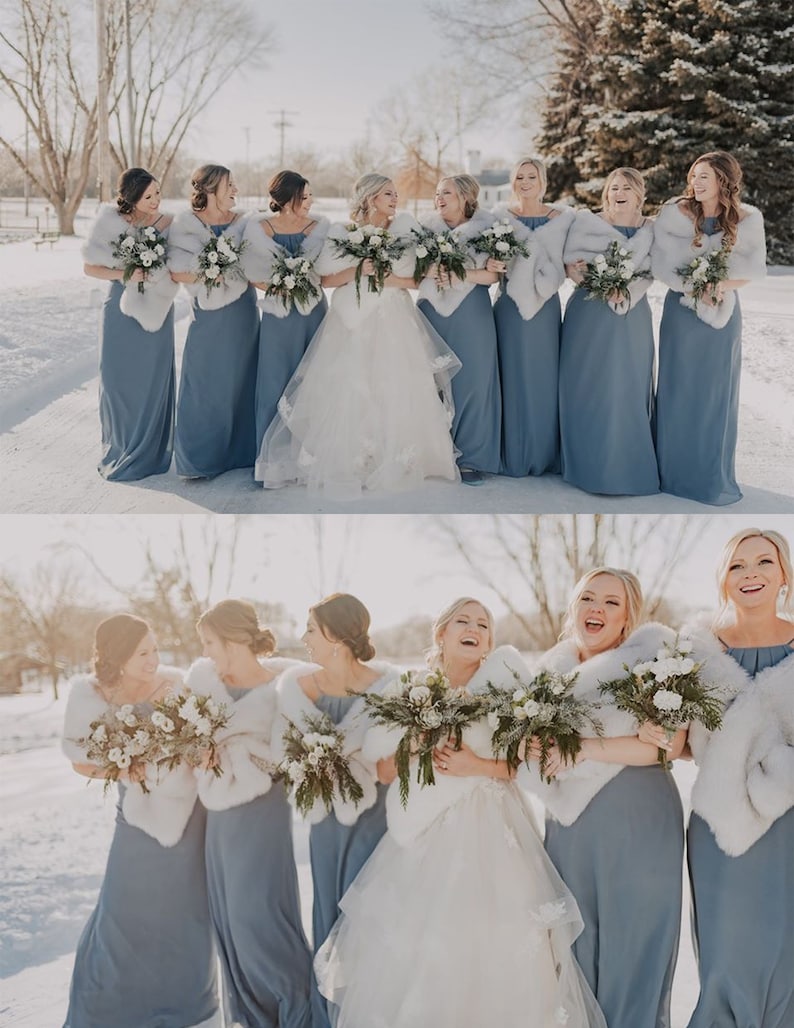 May include: A group of bridesmaids in dusty blue dresses with white faux fur wraps stand in a snowy outdoor setting. They are holding bouquets of white flowers and smiling. The bride is in the center wearing a white wedding dress.