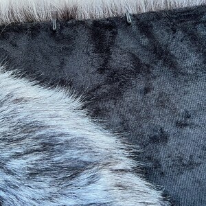 May include: Close-up of a black velvet fabric with a white fur trim. The fur is soft and fluffy, and the velvet is smooth and luxurious.