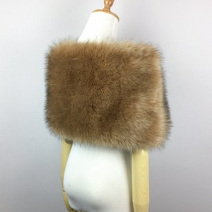 May include: A brown faux fur shawl with a soft, fluffy texture. The shawl is draped over a white mannequin.
