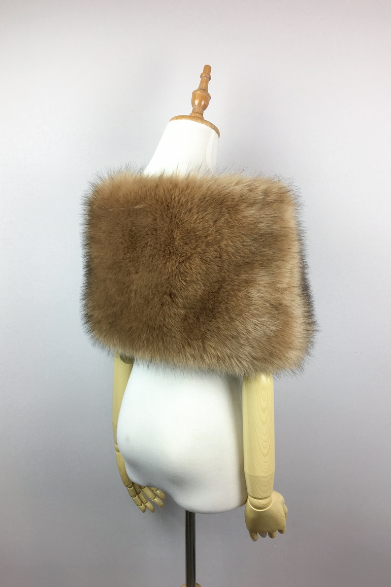 May include: A brown faux fur shawl with a soft, fluffy texture. The shawl is draped over a white mannequin.