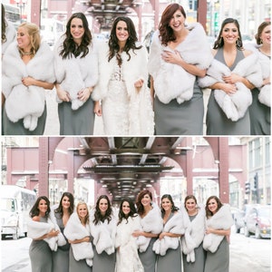 May include: A group of bridesmaids wearing gray dresses and white fur wraps stand in front of a red brick building. The bride is in the center wearing a white lace dress.