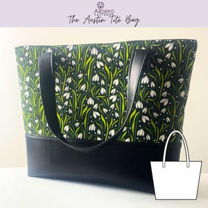 May include: The Austin Tote Bag, a large tote bag with a floral pattern. The top portion of the bag features a dark green fabric with white flowers and green stems. The bottom is solid black. The bag has black handles and the text "Albero Patterns" and "The Austin Tote Bag".