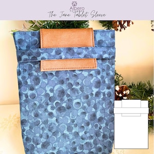 Puede incluir: Una funda azul para tablet con un patrón de círculos superpuestos. Tiene una solapa de cuero marrón y el texto "The Jane Tablet Sleeve". La funda está diseñada para proteger una tablet.