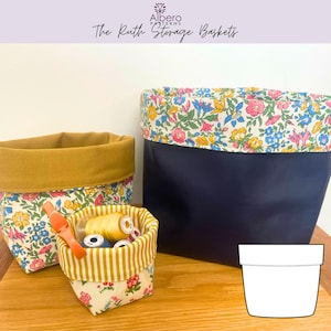 Puede incluir: Tres cestas de almacenamiento de tela de varios tamaños. La más grande es azul marino con un borde con estampado floral. Las otras dos tienen estampados florales con bordes amarillos mostaza y a rayas. La cesta más pequeña contiene carretes de hilo. Texto: "The Ruth Storage Baskets."