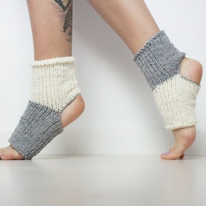 Puede incluir: Un par de calcetines de tobillo de punto gris y blanco con talón abierto. Los calcetines están hechos de un material suave y cómodo y son perfectos para usar en casa o para yoga.