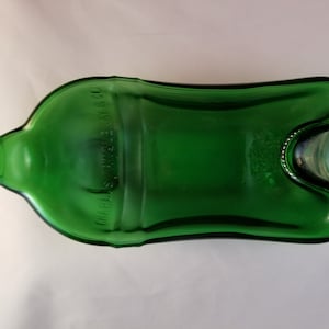 May include: A green glass bottle with a unique shape and a label that reads "Charles S. Welch & Co."