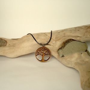 May include: A wooden tree of life pendant necklace with a black cord. The pendant is round and features a detailed carving of a tree with branches and leaves.
