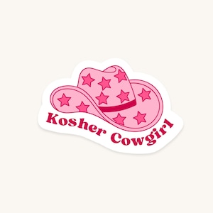 Puede incluir: Una pegatina de sombrero de vaquero rosa con un patrón de estrellas de color rosa oscuro en la copa y el ala. El texto Kosher Cowgirl está impreso en una fuente negrita de color rosa oscuro a lo largo de la curva inferior de la pegatina blanca.