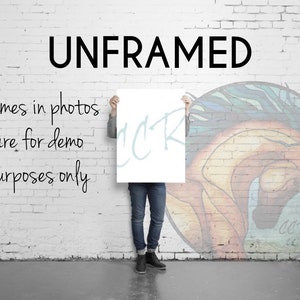 Puede incluir: Una persona sosteniendo un cartel blanco con la palabra "UNFRAMED" impresa en letras negras. El cartel est&aacute; frente a una pared de ladrillo con una pintura colorida de la cabeza de un caballo. El texto "Frames in photos are for demo purposes only" est&aacute; escrito en negro en la pared.
