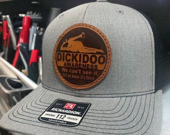May include: Gray and black trucker hat with a brown leather patch that says "Dickidoo Awareness" and "We can't see it, but we know it's there". The hat is adjustable and has a Richardson 112 label.