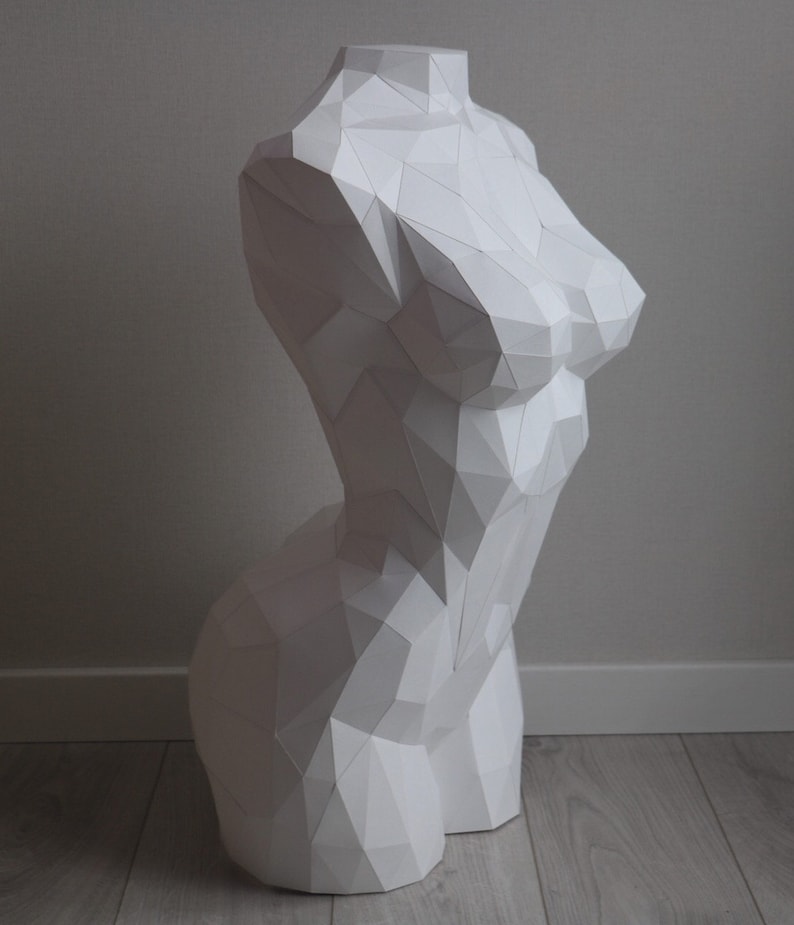 May include: A white, geometric, paper sculpture of a torso.