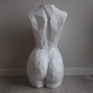 May include: White geometric sculpture of a human torso. The sculpture is made of paper and has a smooth, matte finish.