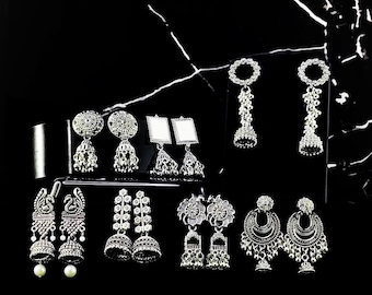 May include: A collection of silver earrings with various designs, including floral, geometric, and traditional Indian styles. The earrings are displayed on a black background.