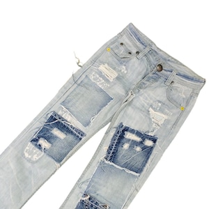 May include: Light blue denim jeans with multiple patches of different shades of blue denim sewn on. The jeans have a distressed look with rips and tears.