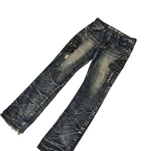 May include: Distressed blue denim jeans with a faded wash and decorative patches. The jeans have a straight leg cut and show signs of wear, with a textured pattern throughout.