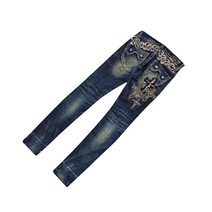 May include: Blue denim jeans with decorative stitching and embellishments. The back pockets feature a cross design and the word "Real" above the pockets. The jeans have a faded wash and a classic five-pocket design.