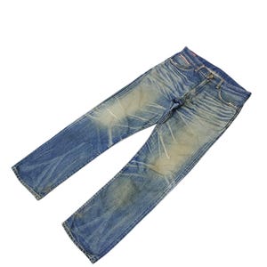 Puede incluir: Vaqueros de mezclilla azul descolorido con un dise&ntilde;o cl&aacute;sico de cinco bolsillos. Los jeans muestran signos de desgaste con ligeros desgastes y decoloraci&oacute;n en toda la tela. Los jeans est&aacute;n planos sobre un fondo blanco.