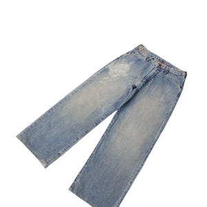 May include: Light blue denim jeans with a faded wash and a straight leg design. The jeans have a classic five-pocket style and a button and zipper closure. The denim has some distressed areas.