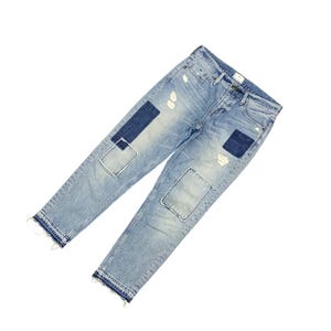 May include: Light blue denim jeans with distressed details and patches. The jeans have a classic five-pocket design, a button and zipper closure, and a raw hem. Patches are sewn on the knees and thigh. The jeans are made of a durable denim material.