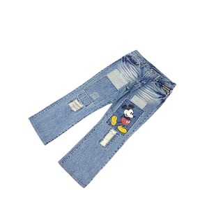 May include: Light blue denim jeans with distressed patches and a Mickey Mouse graphic on the right leg. The jeans have a classic five-pocket design and a straight leg fit. The patches are a lighter shade of blue.