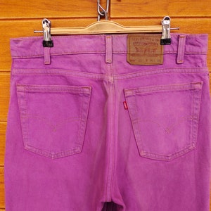 Può includere: Jeans di denim viola con un'etichetta del marchio Levi's sulla tasca posteriore. L'etichetta riporta "Levi Strauss & Co. San Francisco, Calif. Original Quality Clothing" e le informazioni sulle dimensioni "560 W 34 L 30".
