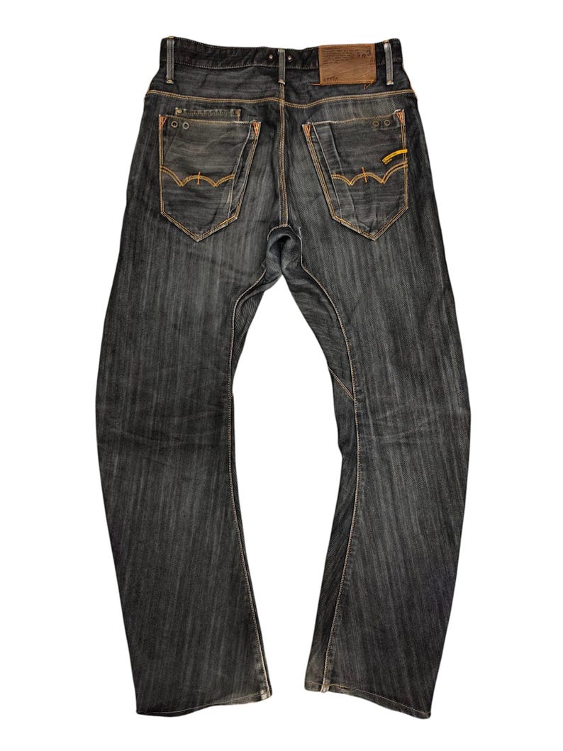 Op de afbeelding: Donkerblauwe denim jeans met een klassiek vijf-zakken ontwerp. Kenmerken zijn oranje stiksels, een leren patch en een subtiele uitlopende beenopening. De jeans hebben een versleten uiterlijk en een knoop- en ritssluiting.