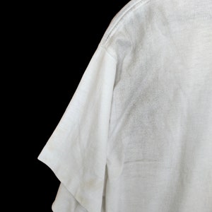 May include: White t-shirt with a short sleeve and a crew neck.