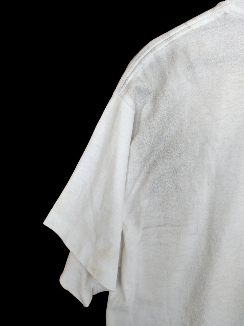 May include: White t-shirt with a short sleeve and a crew neck.