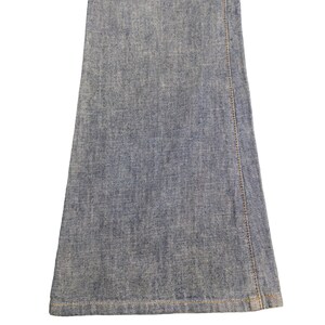 May include: Close-up of the bottom of a pair of blue denim flared jeans. The jeans have a raw hem and are made of a soft, comfortable fabric.
