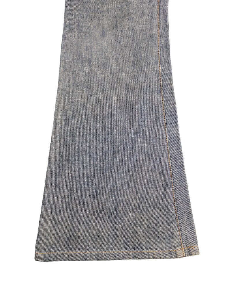 May include: Close-up of the bottom of a pair of blue denim flared jeans. The jeans have a raw hem and are made of a soft, comfortable fabric.