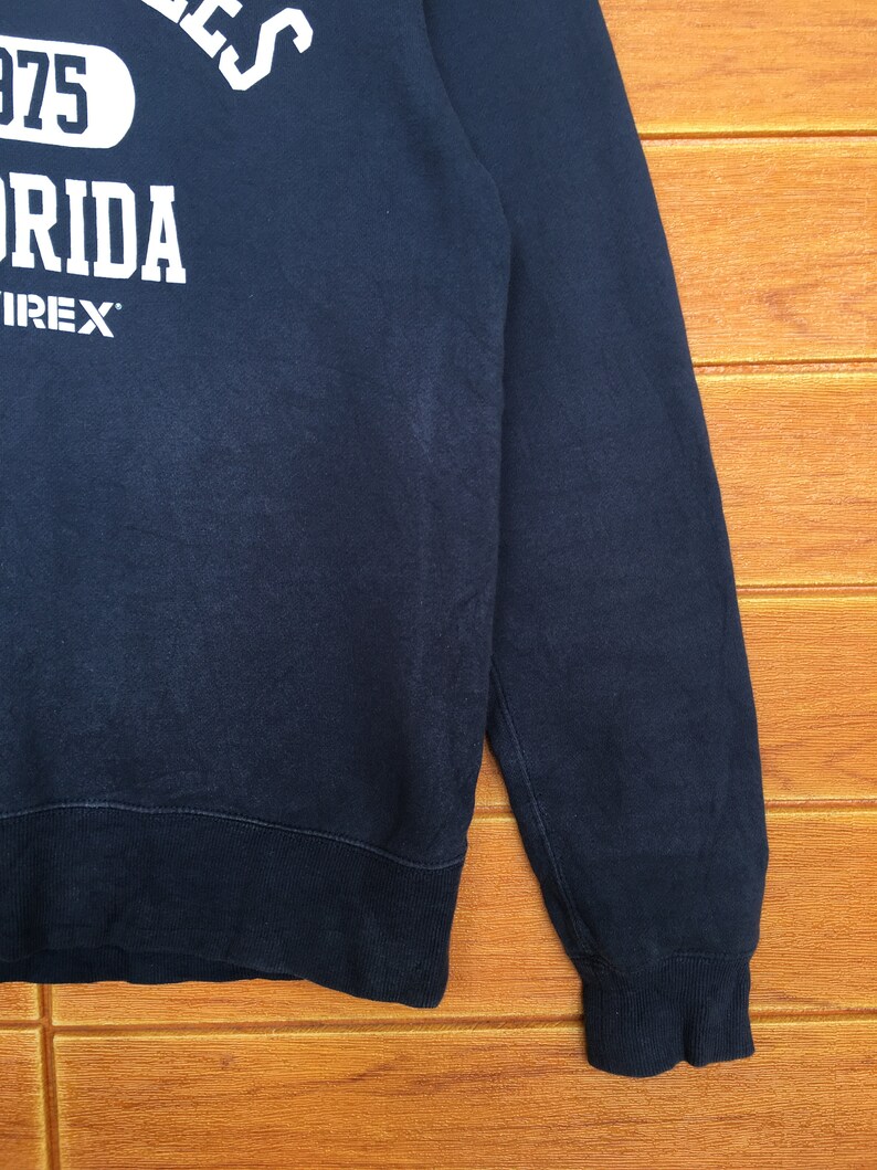 May include: A dark blue sweatshirt with white text that reads "1975" and "Florida" with the word "IREX" underneath.