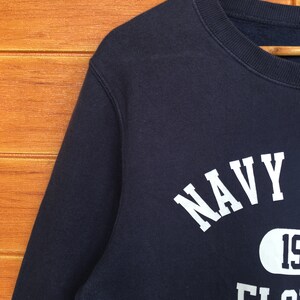 May include: A navy blue sweatshirt with white text that reads "NAVY" and "FLORIDA" with a white circle containing the number "19" in the centre.