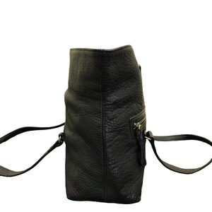May include: A black leather tote bag with two shoulder straps. The bag has a zipped pocket on the front and a zipped closure at the top.