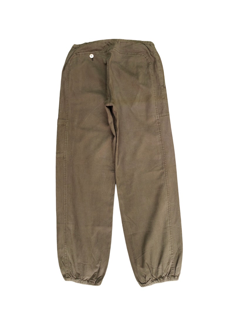 May include: A pair of brown cargo pants with a button on the back. The pants have a drawstring at the bottom of the legs.
