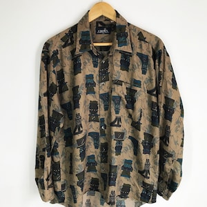 May include: A long-sleeved button-down shirt with a brown background and a blue, black, and green abstract pattern. The shirt has a label that says "CHOPEN".