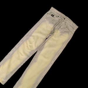 Könnte beinhalten: Eine hellblaue Jeans mit weißen Streifen. Die Jeans hat einen verblassten, abgenutzten Look und ist mit weißen Farbspritzern bedeckt.