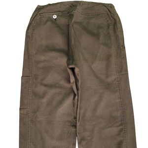 May include: A pair of brown cargo pants with a button on the back. The pants have a relaxed fit and are made of a durable fabric.