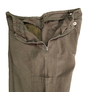 May include: A pair of brown cargo pants with a zipper and button closure. The pants have a pocket on the right leg.