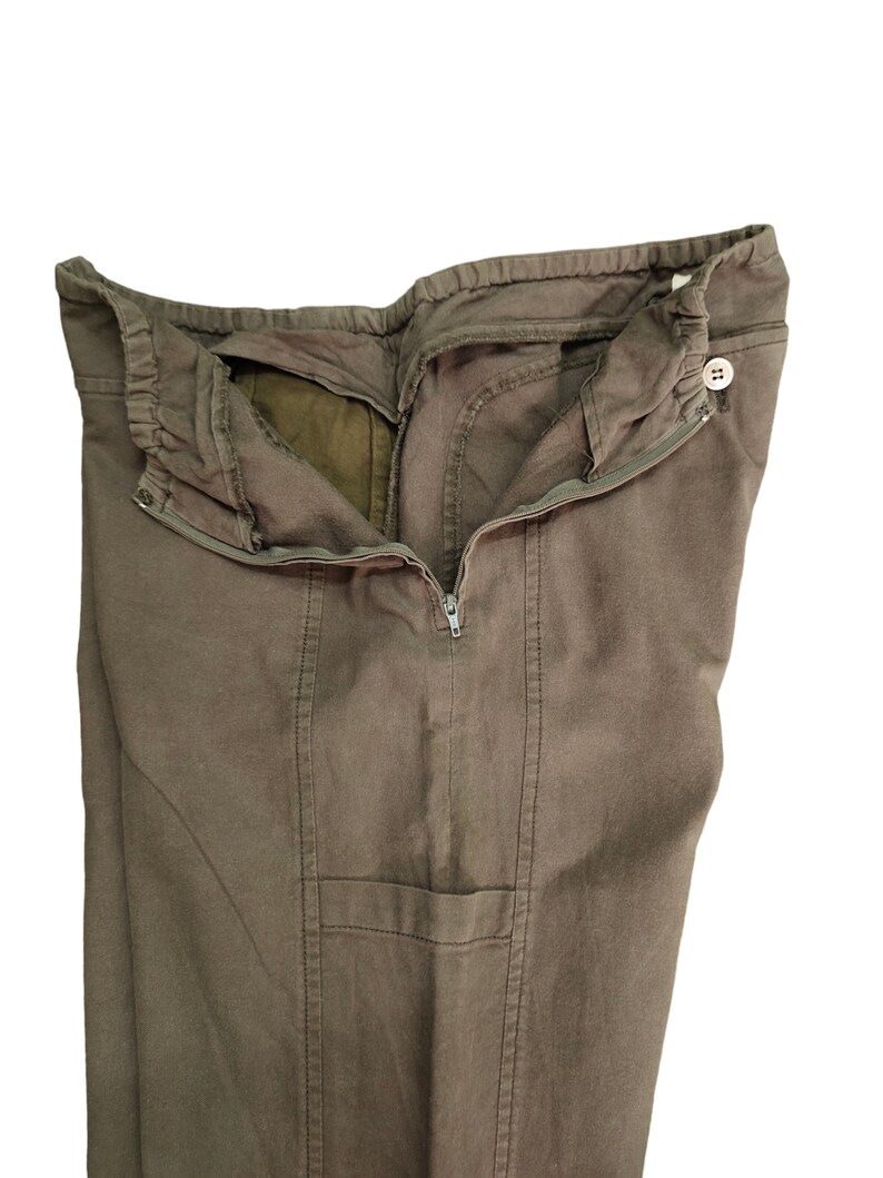 May include: A pair of brown cargo pants with a zipper and button closure. The pants have a pocket on the right leg.